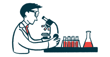 A researcher uses a microscope in a lab alongside a rack of vials and a full beaker.