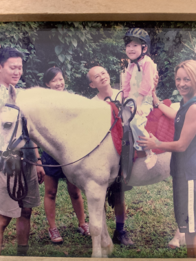 grief and trauma | SMA News Today | a faded picture of people surrounding Sherry as a young girl. She's seated on a white horse, smiling at the camera.