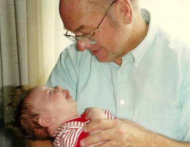 sma treatment | SMA News Today | a photo of of Helen's dad, wearing glasses and a white short-sleeve shirt, holding Jeffrey, who is in a red-and-white-striped shirt.