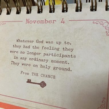 The photo shows a calendar entry of a spiral collection that's the size of an index card and has a red boundary line and the words "November 4" at the top. It reads, in black type with a key image beneath it, "Whatever God was up to, they had the feeling they were no longer participants in any ordinary moment. They were on holy ground. From THE CHANCE."