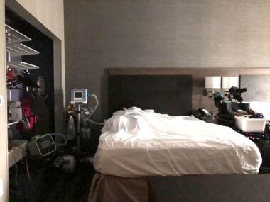 A photo of an accessible hotel room, with several amenities tailored to people with disabilities and/or in wheelchairs. Visible in the photo is a bed, some medical equipment, and a closet with shelves.