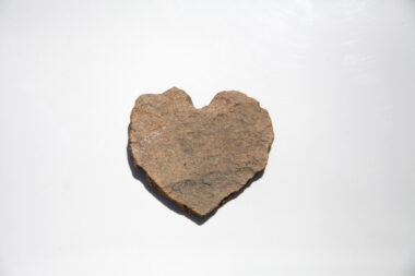 A heart-shaped rock set to a simple white background.