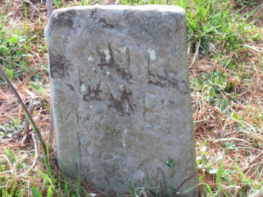 A low stone marker amid brown and green grass.