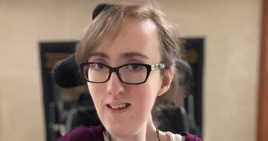 A close-up head shot of a woman with glasses.