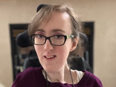 A close-up head shot of a woman with glasses.