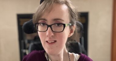 A closeup profile of a woman with black glasses whose head is turned slightly to the right as she looks at the camera.