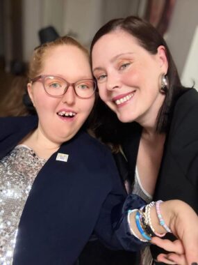 A woman and a teenage girl are shown dressed up and smiling.