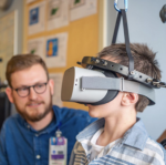 A child uses a virtual reality headset as a clinician looks on.