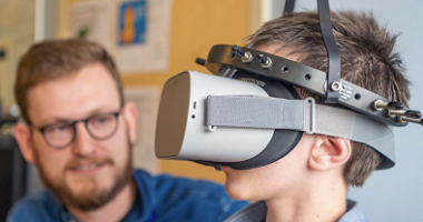 A child uses a virtual reality headset as a clinician looks on.