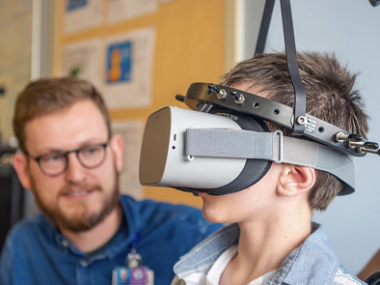 A child uses a virtual reality headset as a clinician looks on.