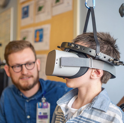 A child uses a virtual reality headset as a clinician looks on.