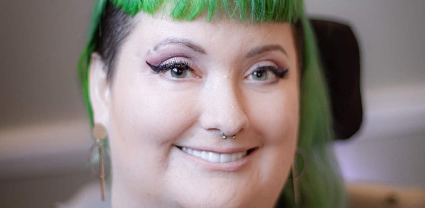 A headshot, seen close up, shows a woman with black and green hair.