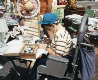 A boy sits at a desk, drawing.