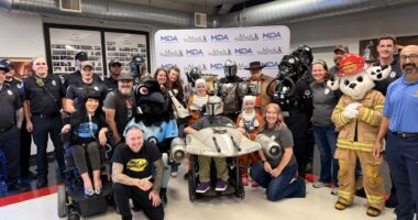 A group is gathered around a boy in a Star Wars-inspired custom wheelchair costume.