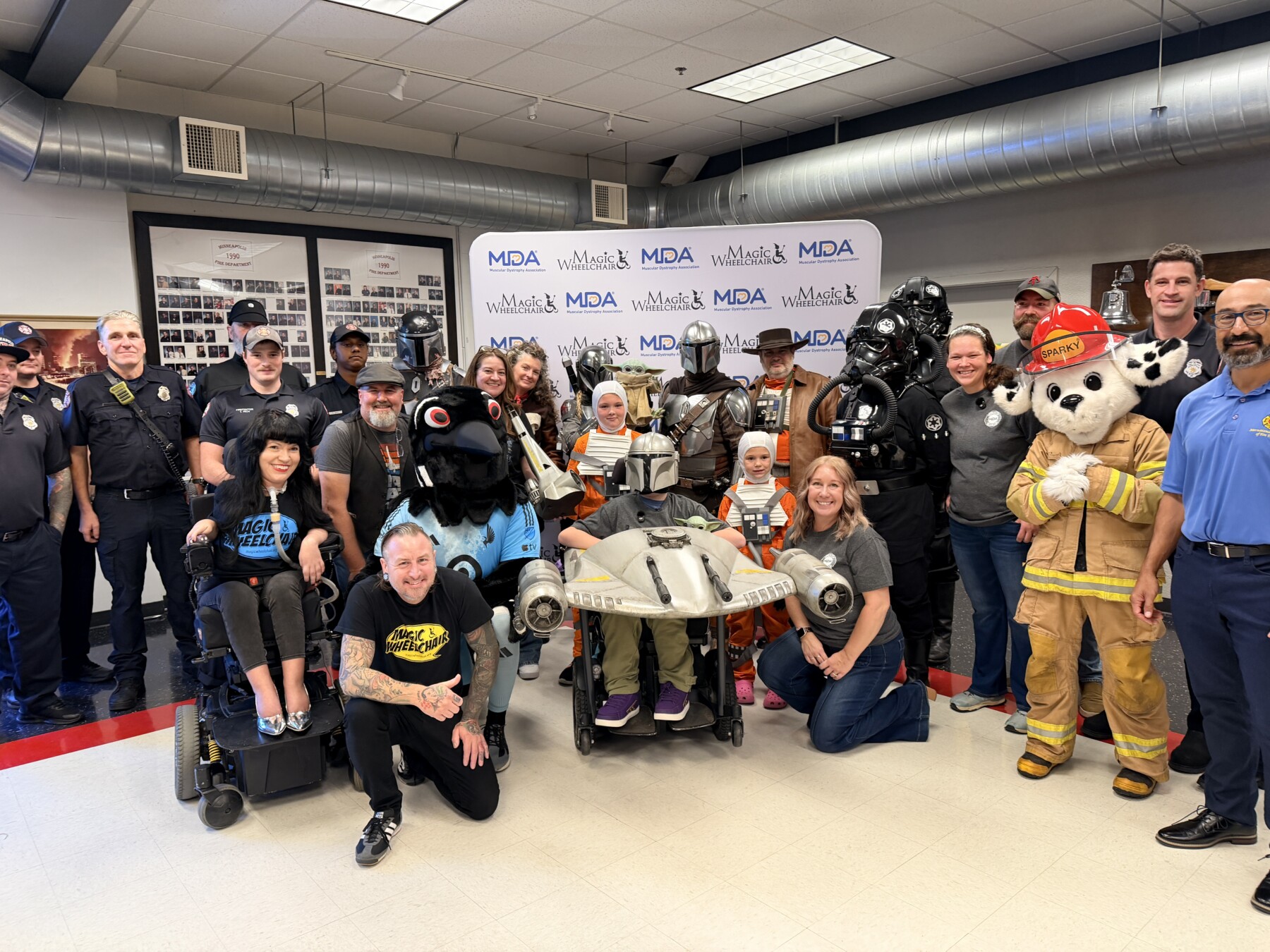 A group is gathered around a boy in a Star Wars-inspired custom wheelchair costume.